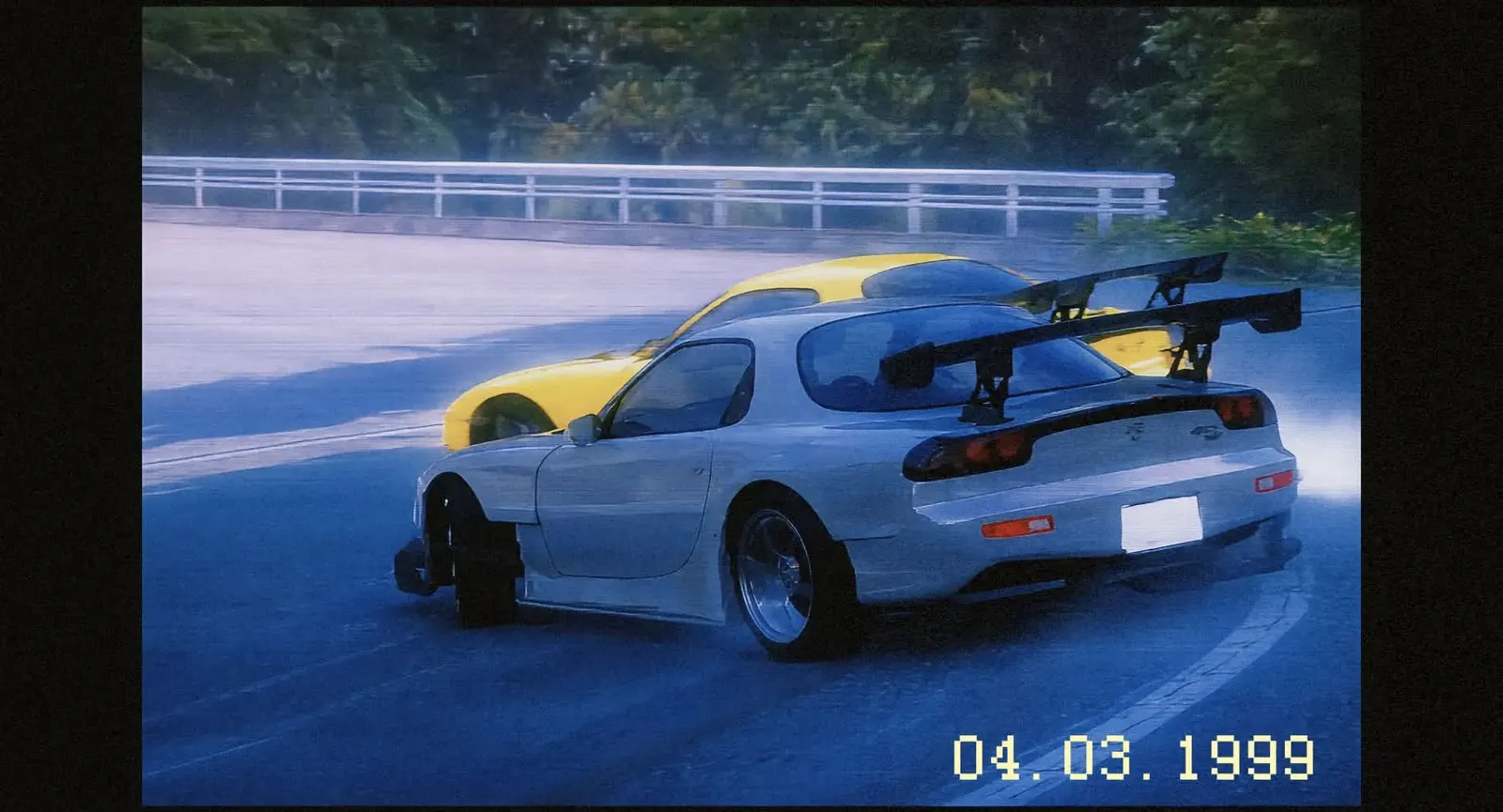 Two RX-7 FD3S drifting side by side through a corner, in an in-game replay